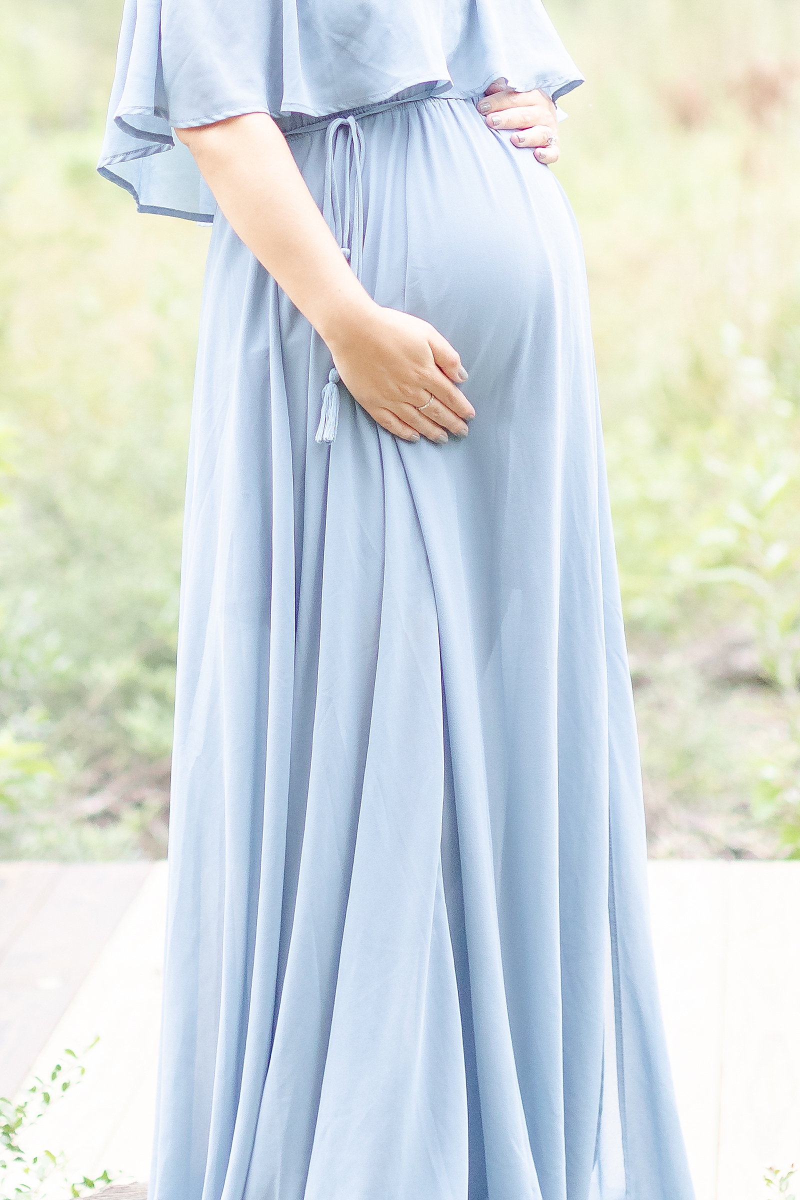 detail shot of baby bump with mom wearing blue gown during rainbow baby maternity session in Houston