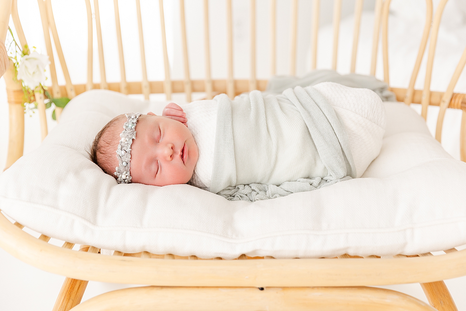 newborn baby asleep on a boho chair swaddled wearing headband at lifestyle newborn session