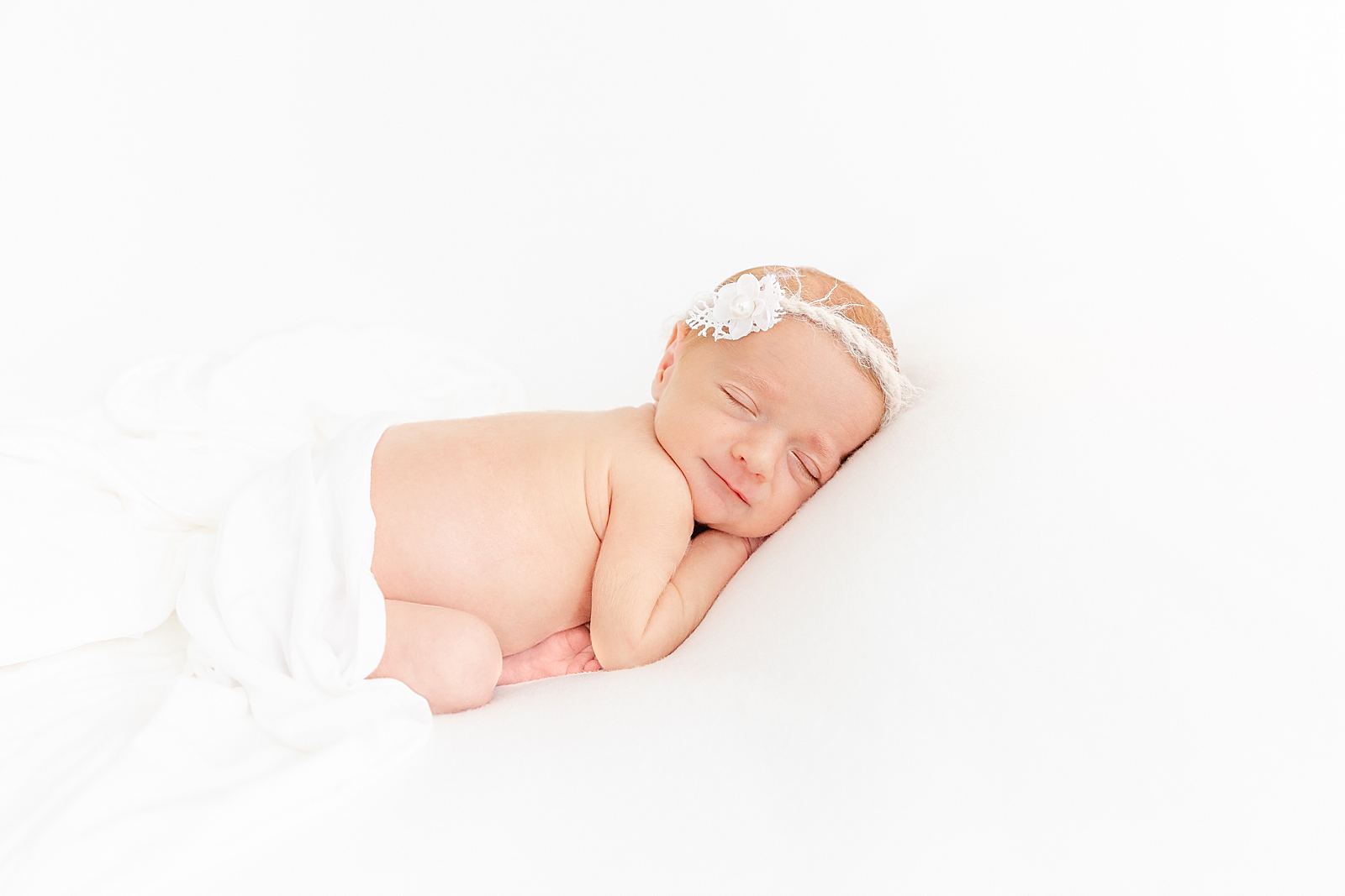 Preemie Newborn Session of posed baby girl on white backdrop with white headband