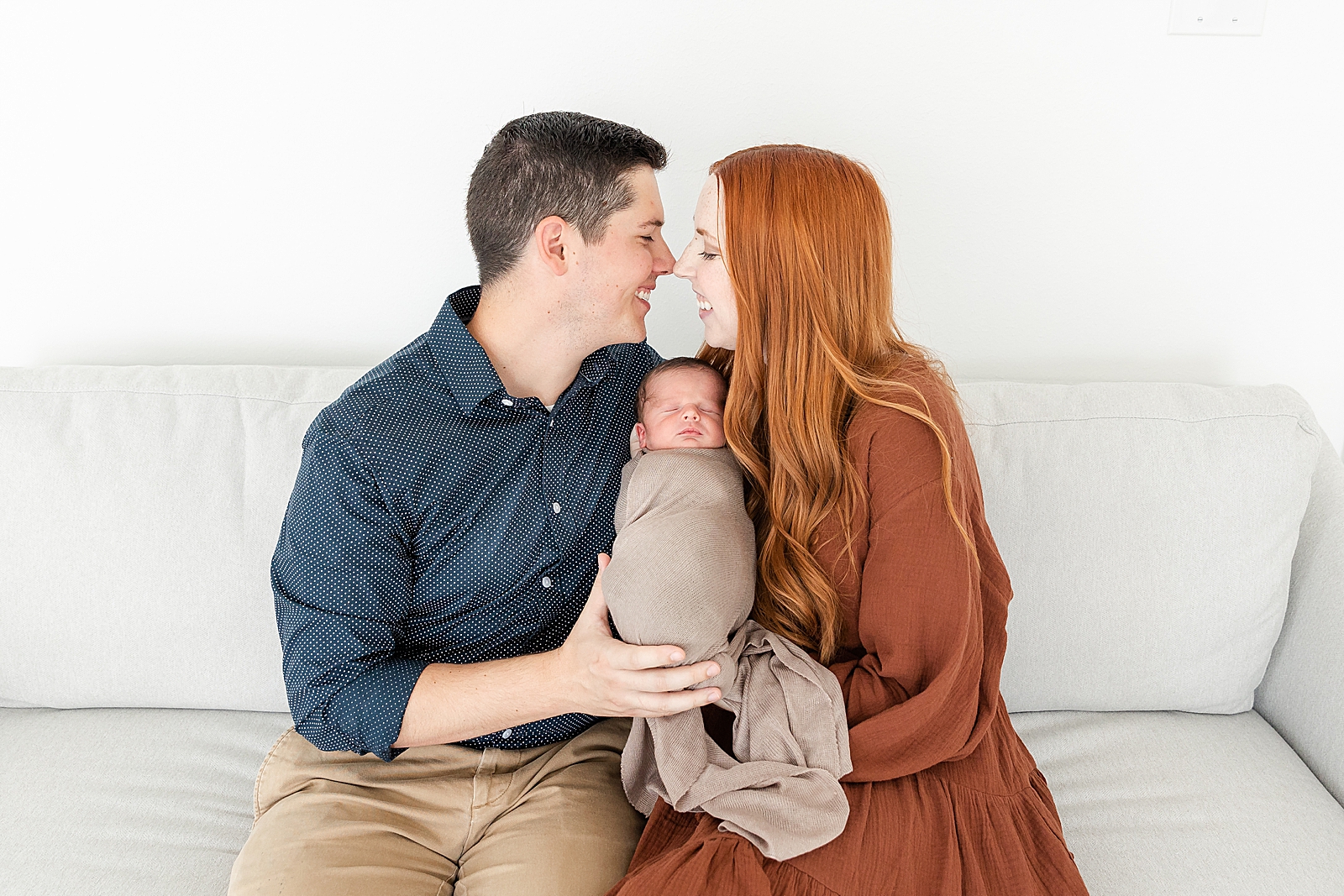 mom and dad smiling over baby for newborn photos