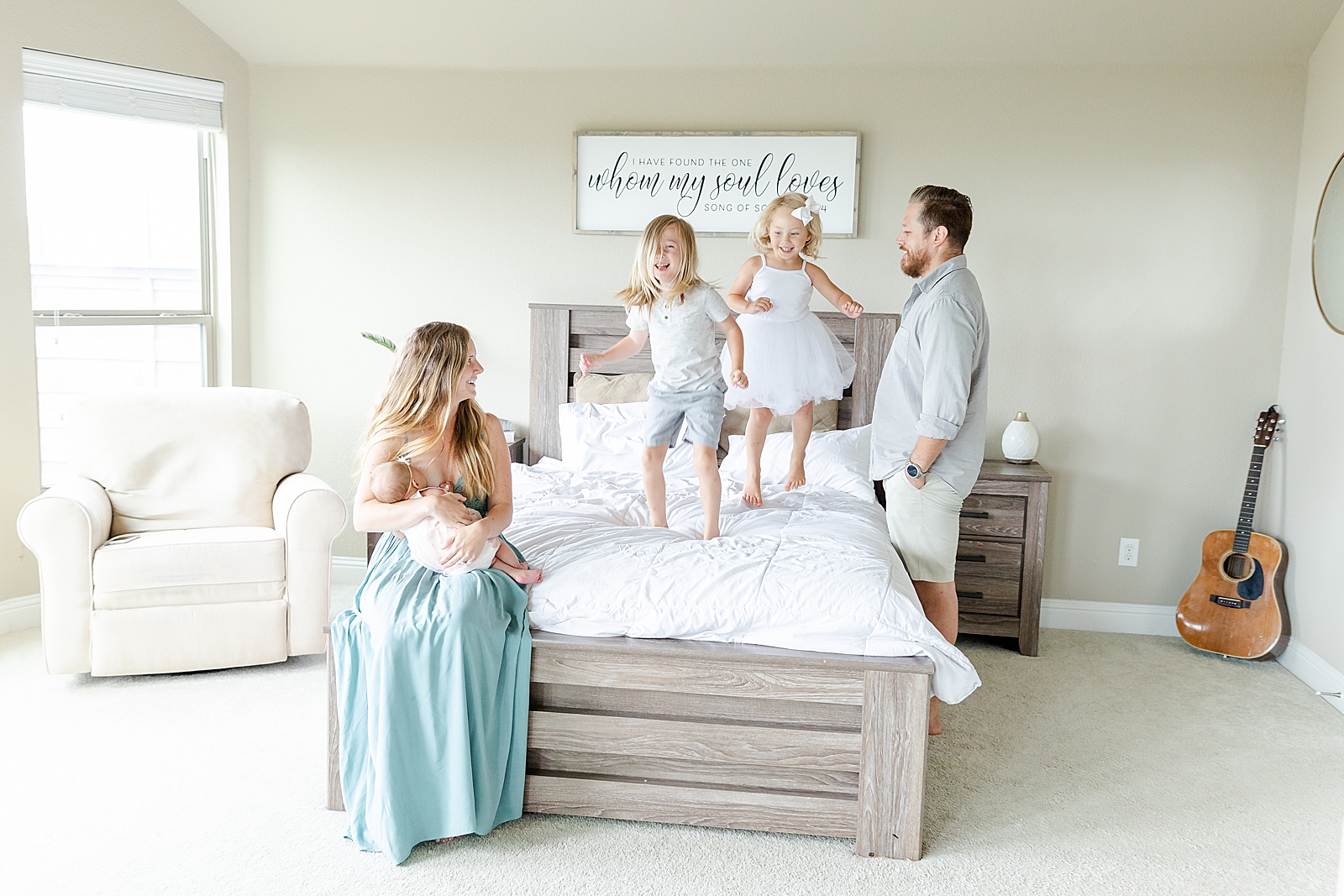 siblings jumping on bed while mom nurses baby and dad plays with kids while they jump