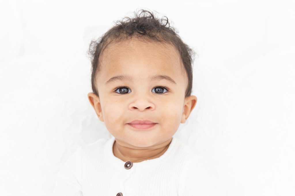 one year old boy looking at camera with white backdrop