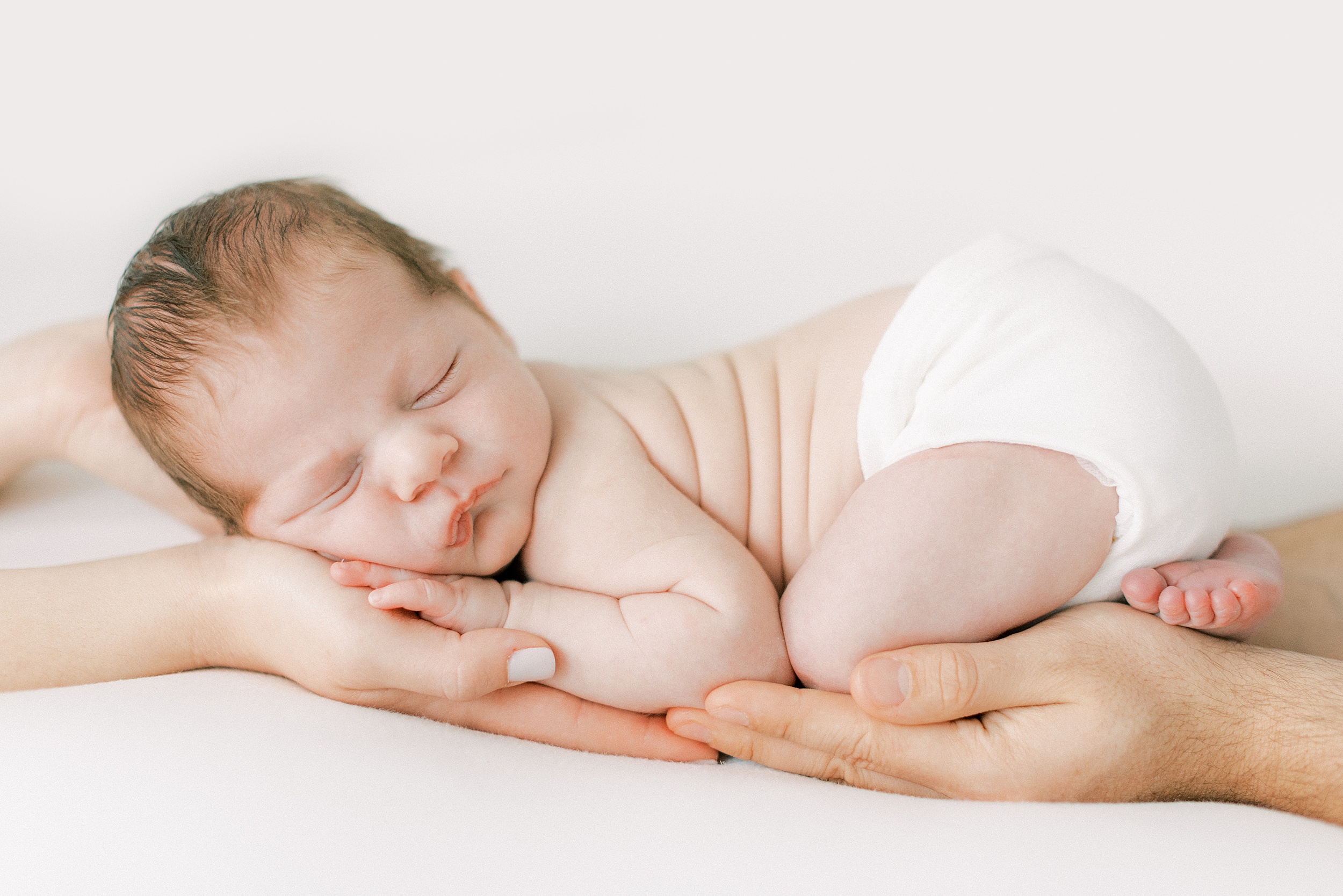 A newborn baby sleeps on mom and dad's hands night nurse dallas